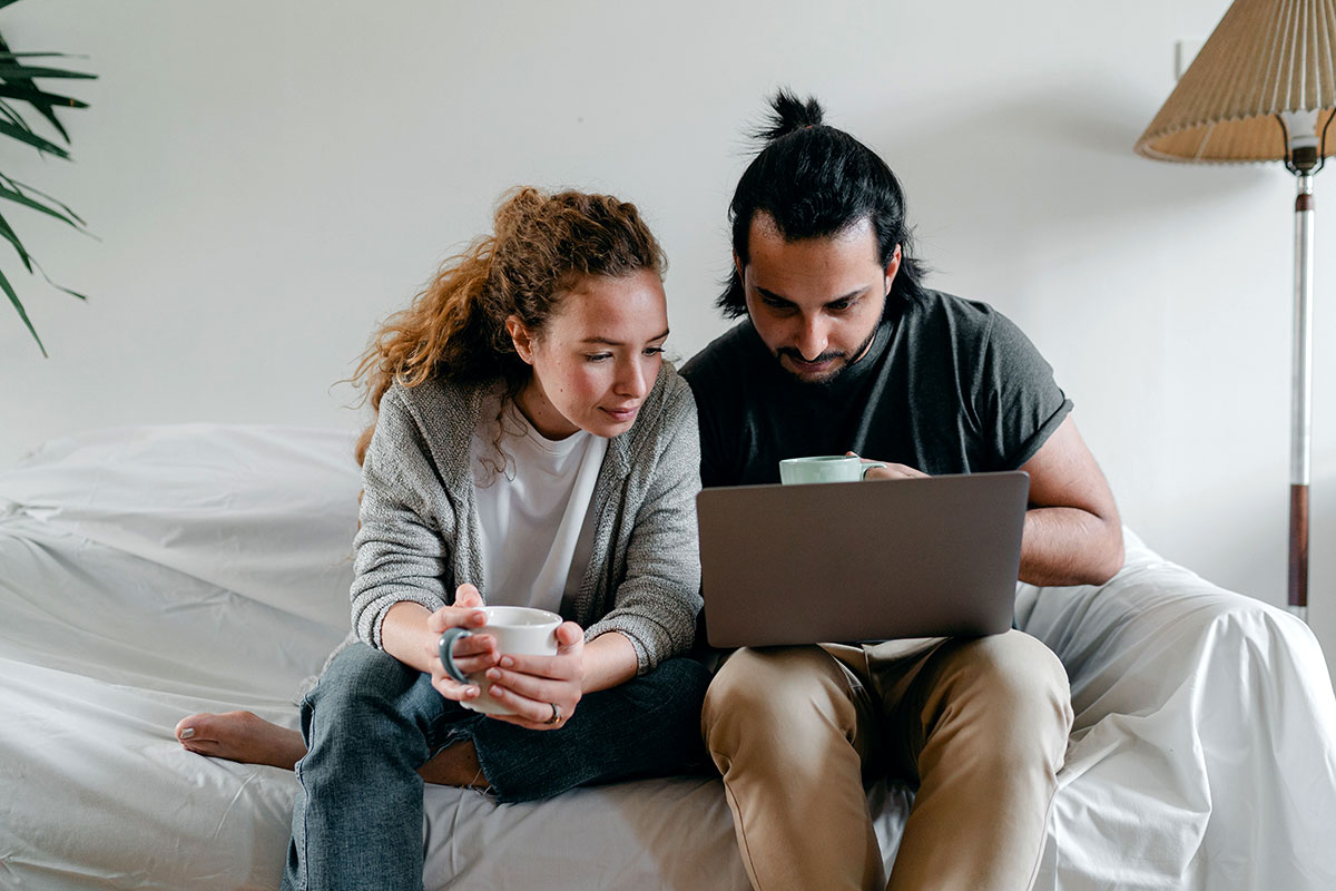 Una pareja de jóvenes consultan un ordenador portátil