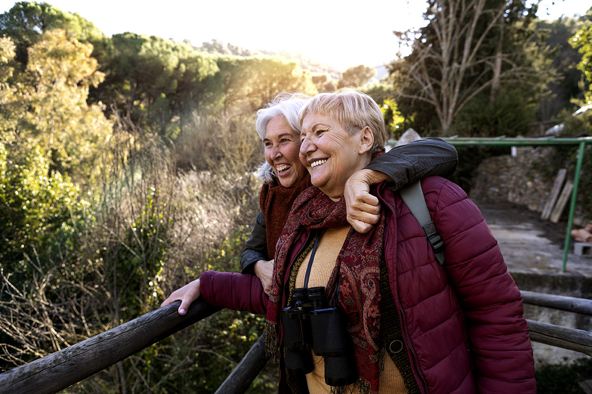 Dos mujeres mayores sonrien abrazadas en un entorno turístico rural