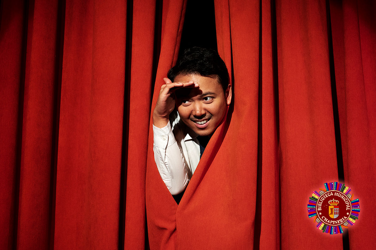 Un actor de teatro asoma la cabeza a través del telón